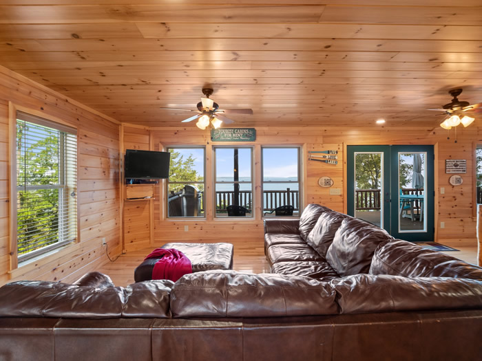 Living room area with windows showing the lake. As the sign in the living room says, our cabin has electricity and indoor plumbing.
